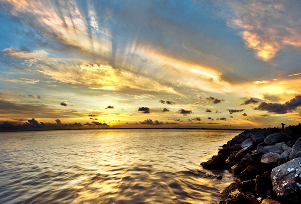Dramatic pastel light sunset with sun rays in Santa Rosa Beach, Florida with Pensacola coastline coast cityscape skyline in FL panhandle 